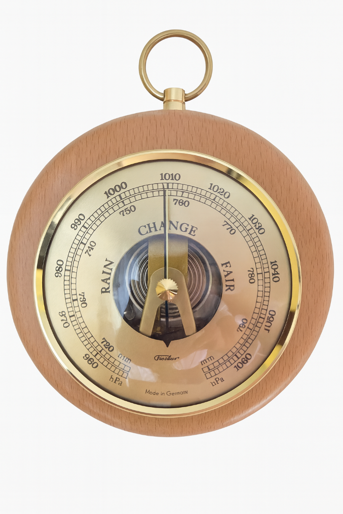 Round German barometer with brass trim and wood frame, displaying air pressure readings.