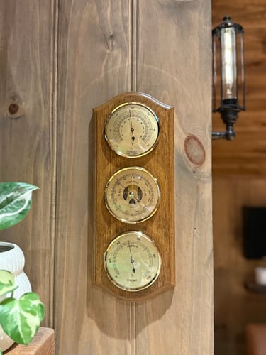 Wooden weather station with barometer, hygrometer, and thermometer on wall indoors
