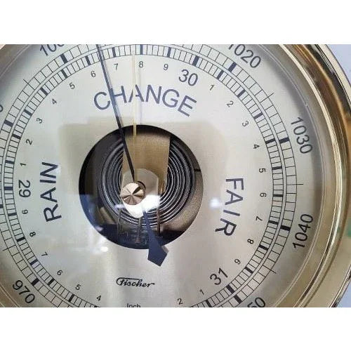Analog German barometer with brass frame, displaying weather conditions and pressure.