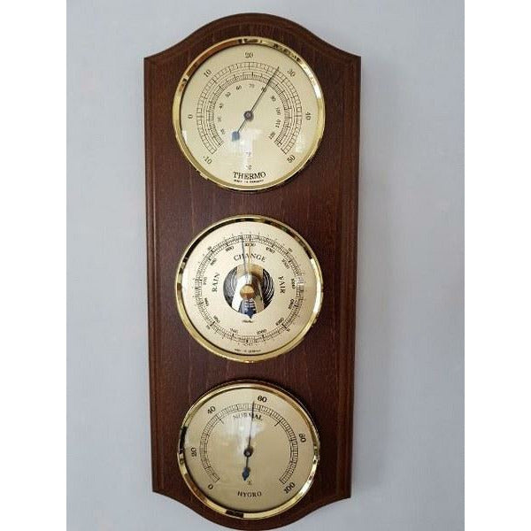 Wall-mounted weather station with barometer, thermometer, and hygrometer on wood panel