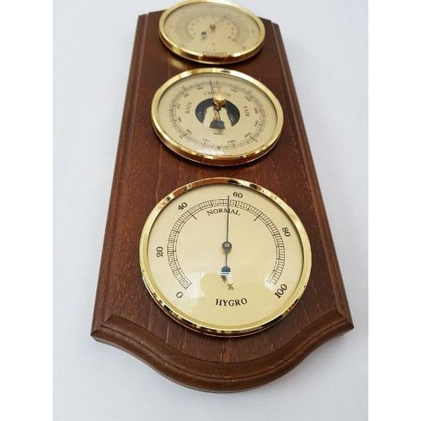 Wooden wall-mounted weather station with barometer, hygrometer, and clock dials
