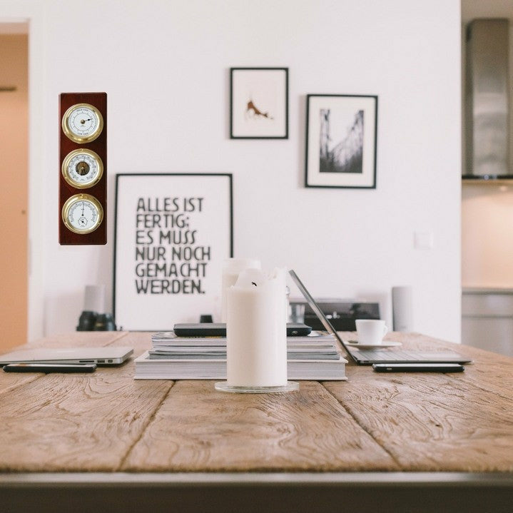 Wooden tide clock and weather station with gold dials mounted on a wall in a modern office