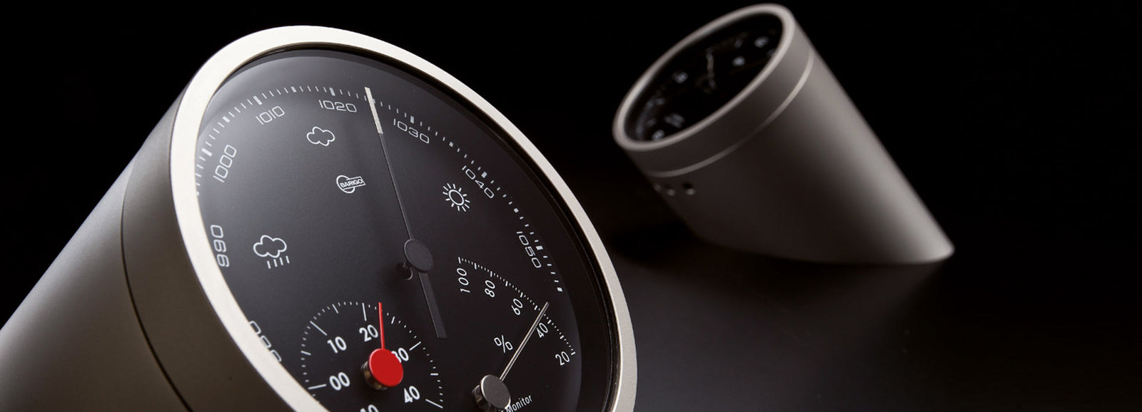 Modern German barometer and hygrometer with sleek metal casing on dark background