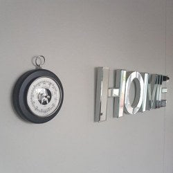 Wall-mounted German barometer next to decorative HOME letters on light gray wall