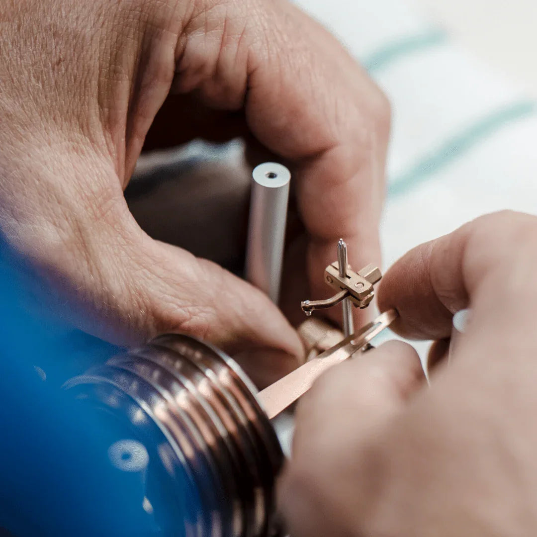 Hands assembling a precision German barometer mechanism, close-up view